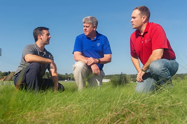 Jake Doskocil, PhD (right) and Laurence Mudge (center) talking with a Bayer customer (left) in the field at the Bayer Research and Education Facility in Clayton, North Carolina.