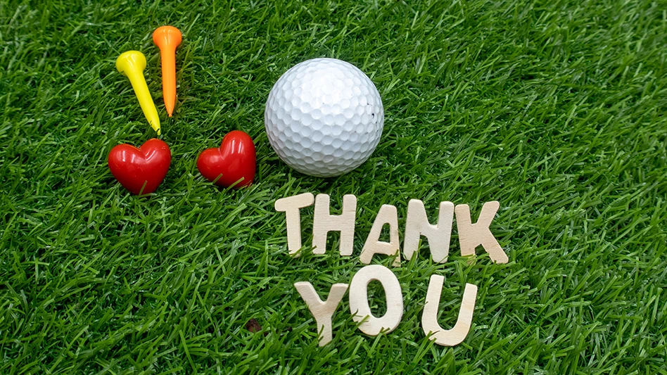 A playful display of a golf ball, tees, hearts and letters spelling "THANK YOU."