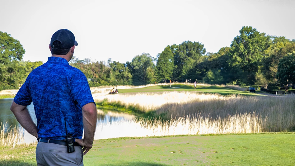 A golf course superintendent gazing in the distance on a golf course
