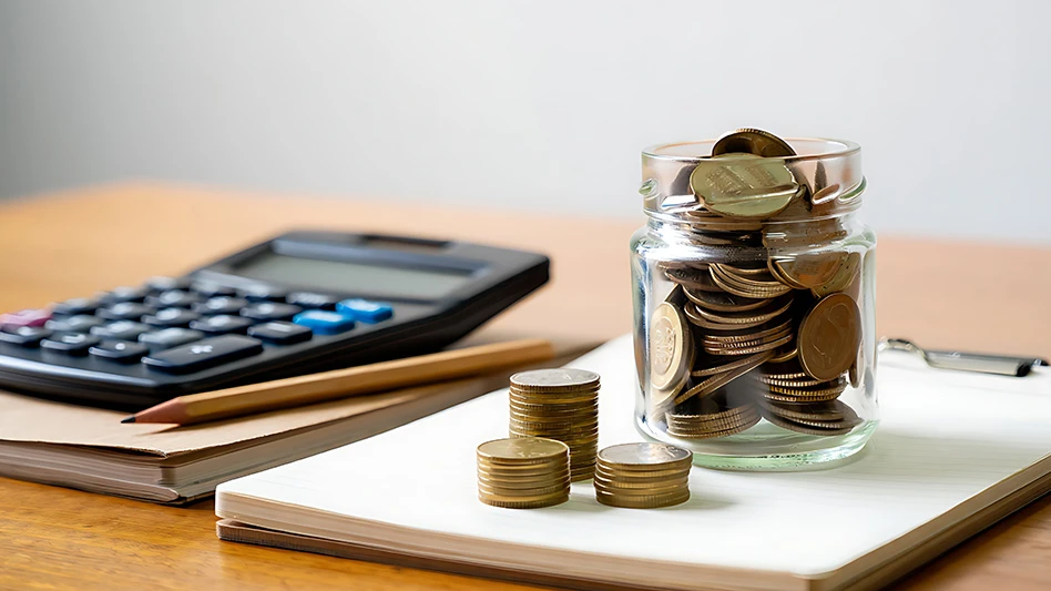 A jar of coins on top of a clipboard, next to a calculator and pencil.