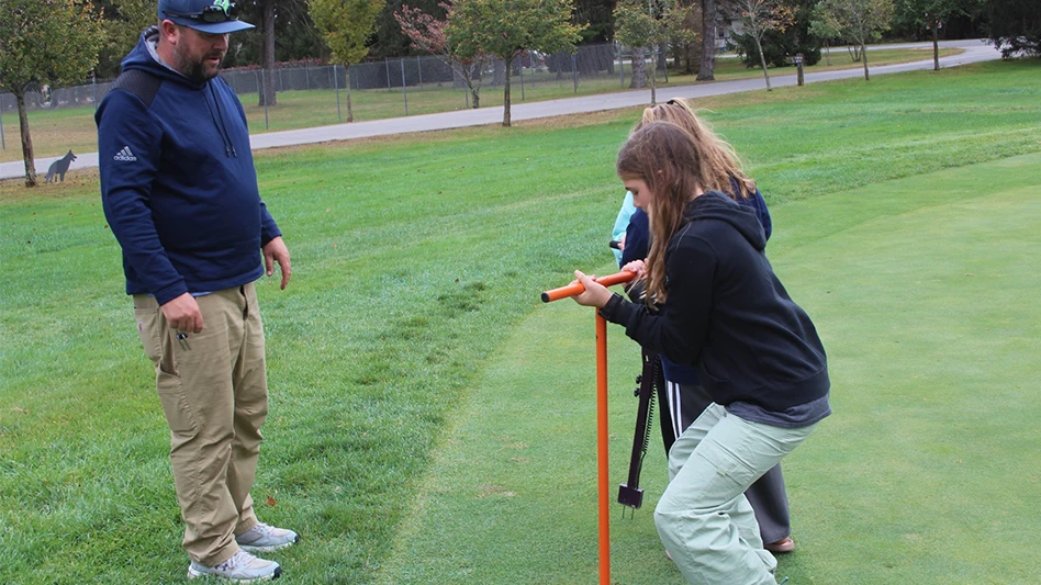 Two girls working on a green with a man